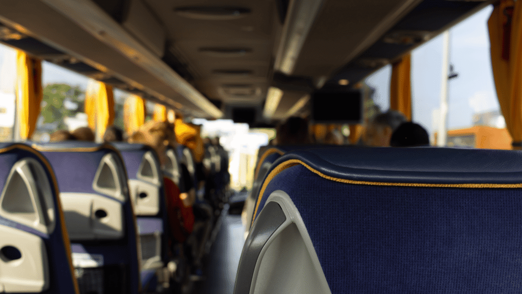 Interior of a charter bus showing empty and occupied navy blue seats with yellow trim, highlighting true luxury charter bus experience.